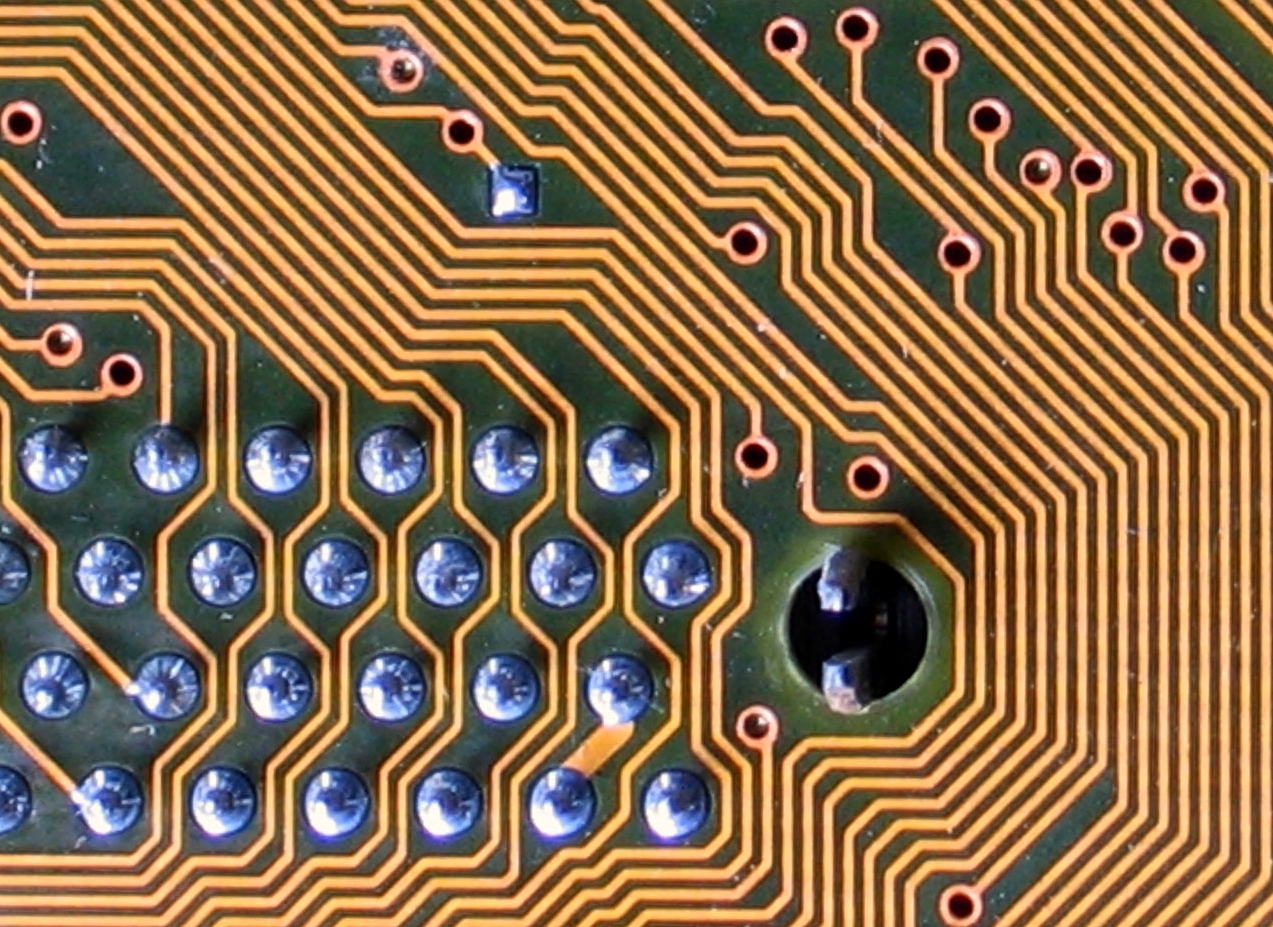 Macro shot of PCB copper traces and through-hole solder joints